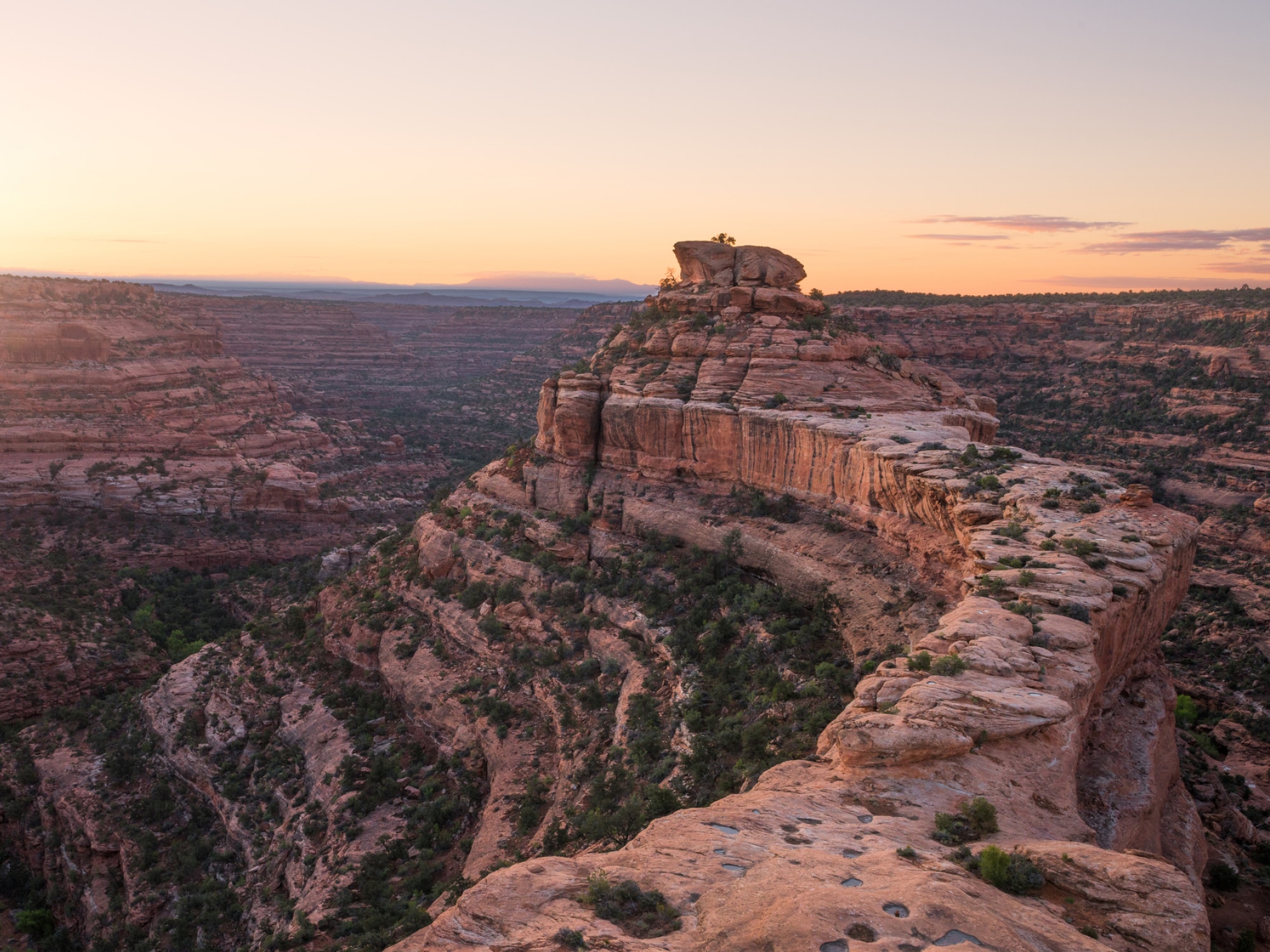 A bird’s eye view of a large rock formation with a sunset in the background.