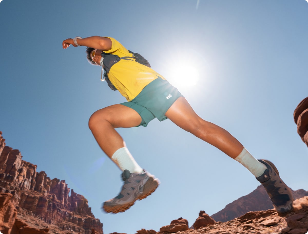 A person running through a rocky trail on a sunny day.