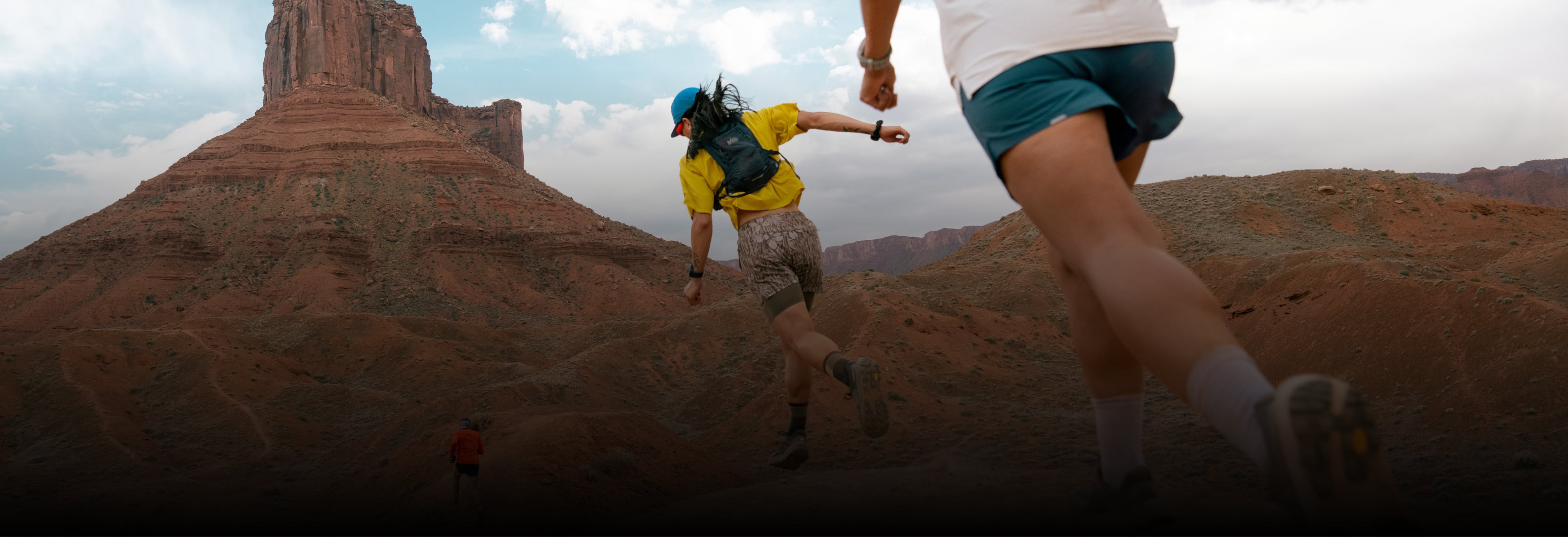 Two people running together through a rocky trail.