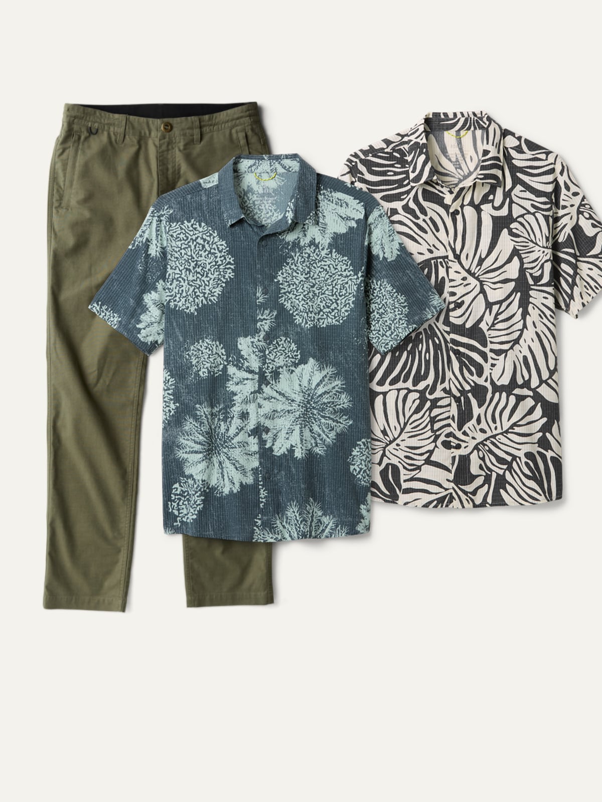 Two Roark button up shirts and a pair or pants on a light colored background.