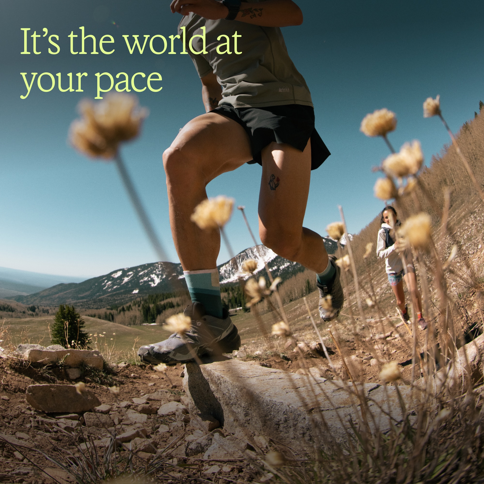 Text reads: ‘It’s the world at your pace’ over an image of flowers with two people trail running in the background.