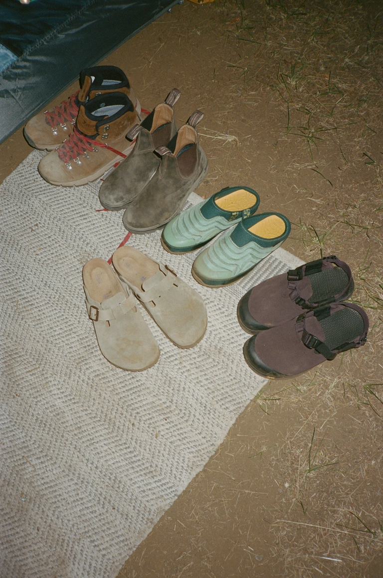 A group of shoes on a mat outside a tent.