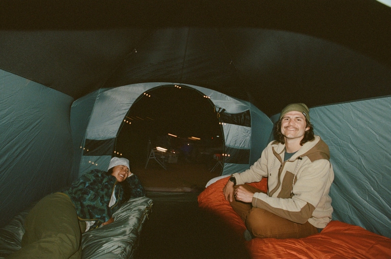 Two people inside a tent, wearing fleece jackets