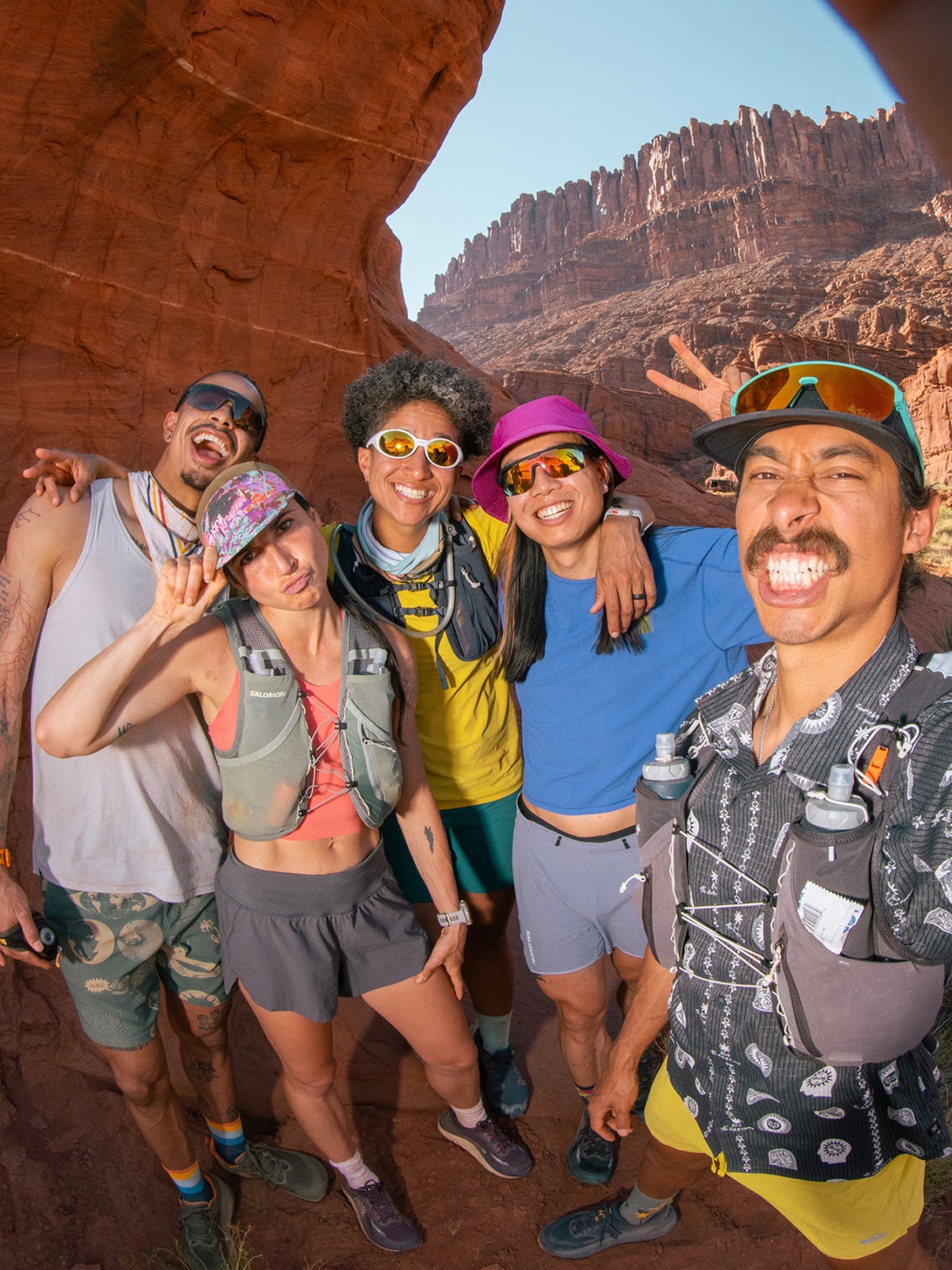 A group of people stand underneath a large rock formation and pose for the camera.