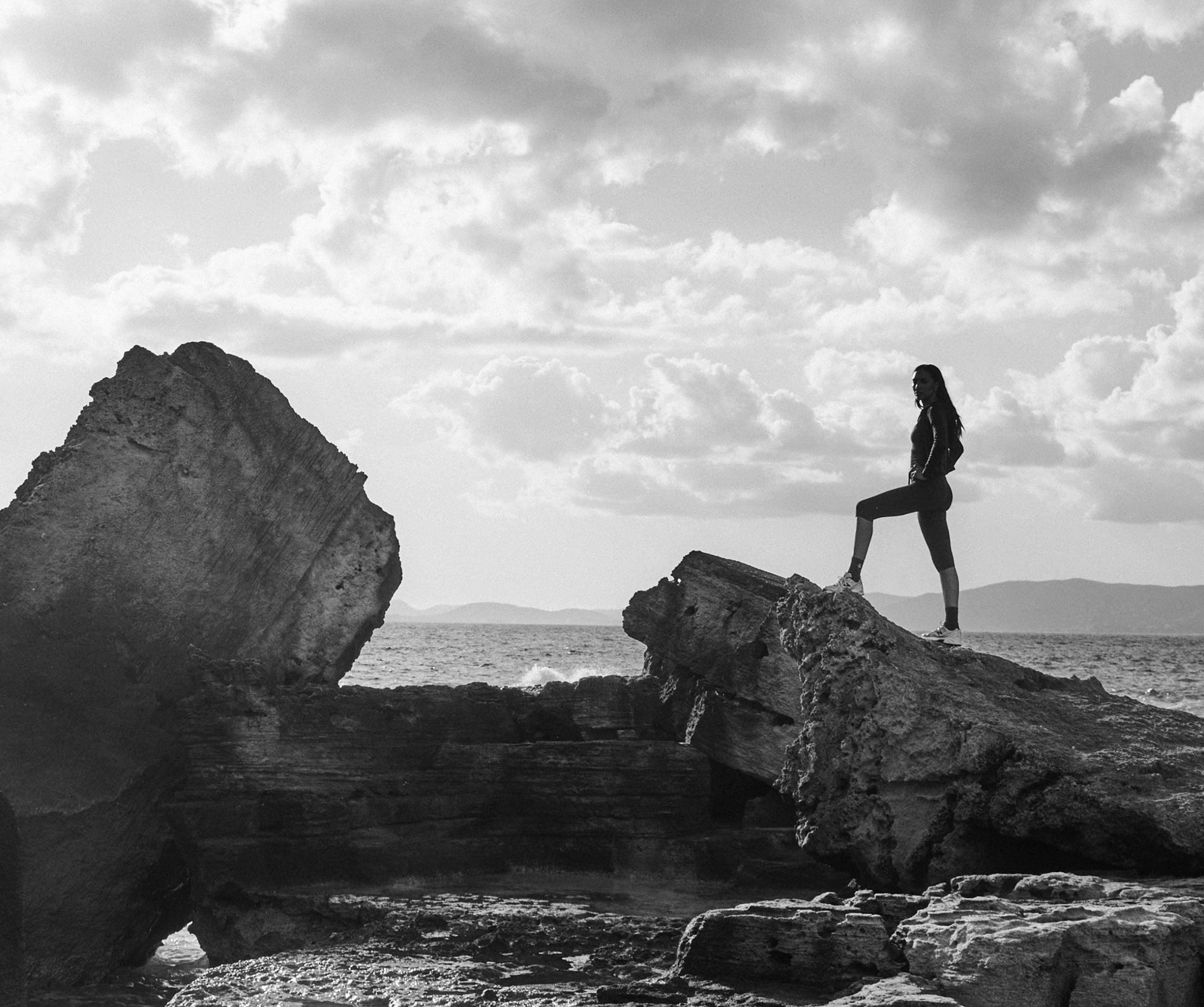 A person stands on top of a rock and poses for the camera.
