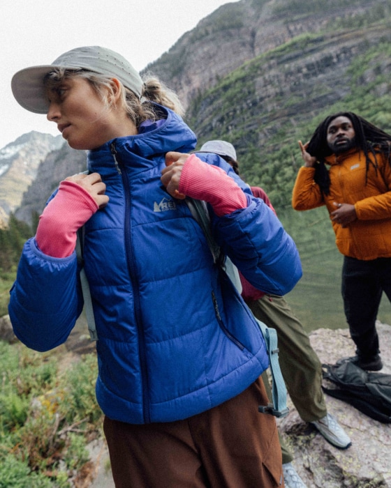 Three people put their backpacks and jackets on before starting their hike.