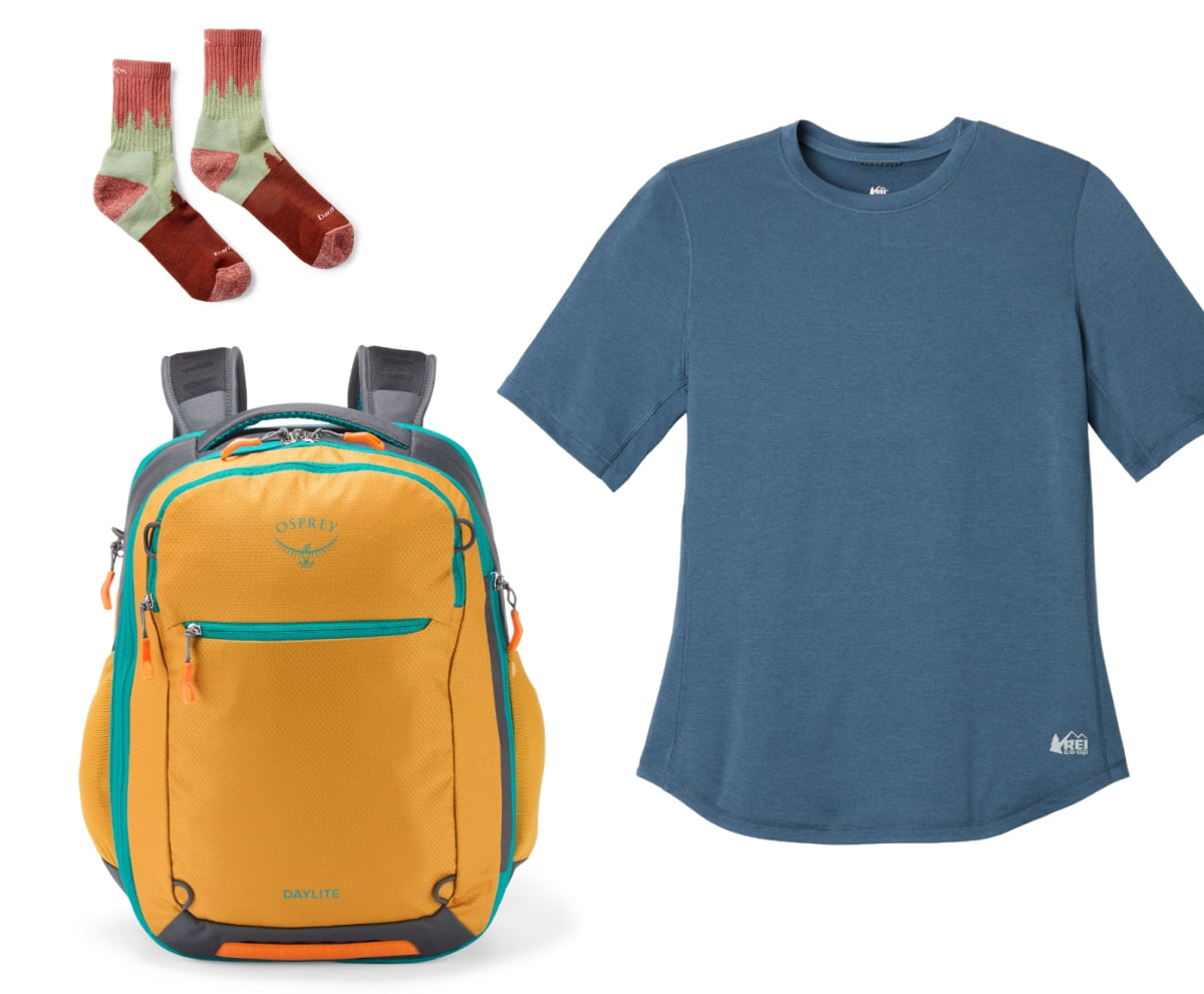 An Osprey pack, Darn Tough socks, & an R E I Co-op brand t-shirt on a light colored background.
