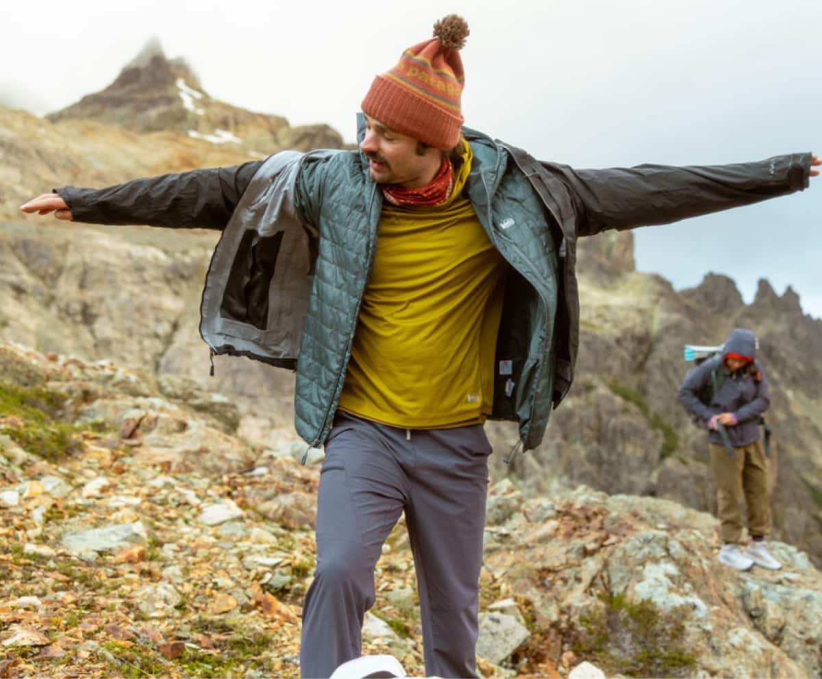 A person stops to put their jacket on during a hike.