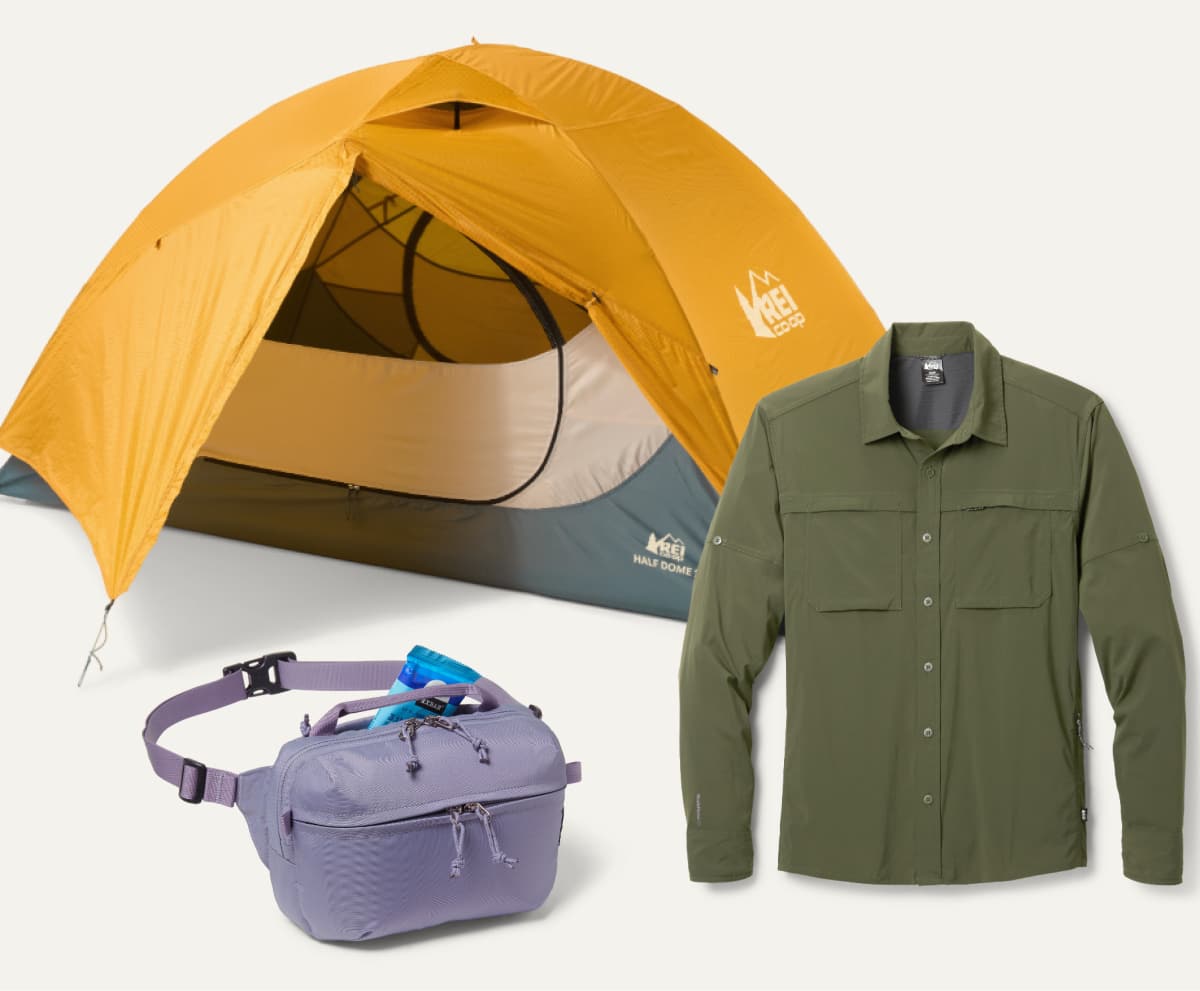 An R E I Co-op brand tent, waist pack, & long-sleeve shirt on a light colored background.