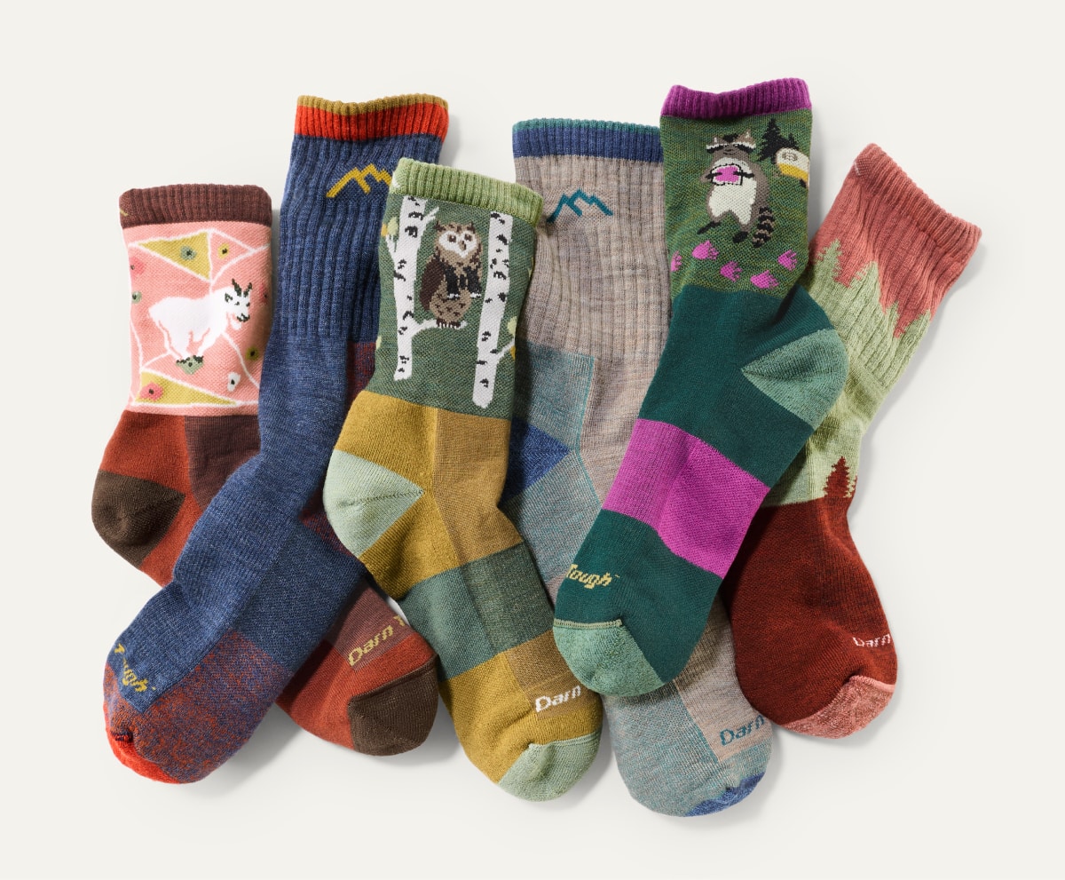 A collage of colorful Darn Tough socks on a light colored background.