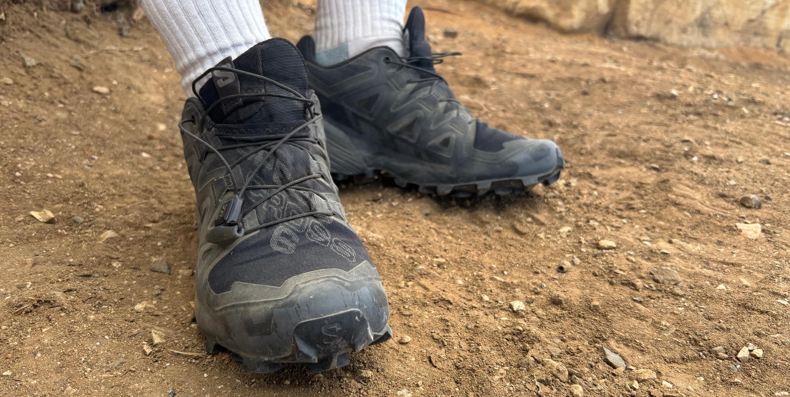 A runner's feet in the Salmon Speedcross 7 trail-running shoes in black and a white pair of socks.