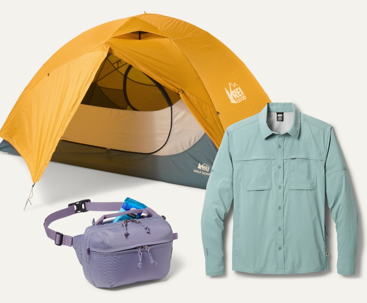 An R E I Co-op brand tent, waist pack, & long-sleeve shirt on a light colored background.