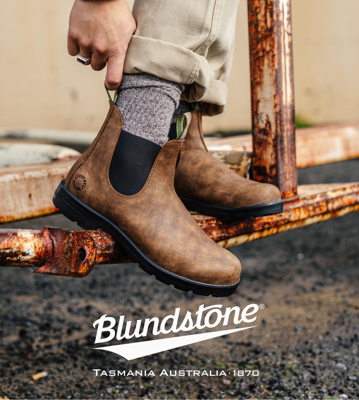 A person uses the pull tab to slip their foot into their Blundstone boots.