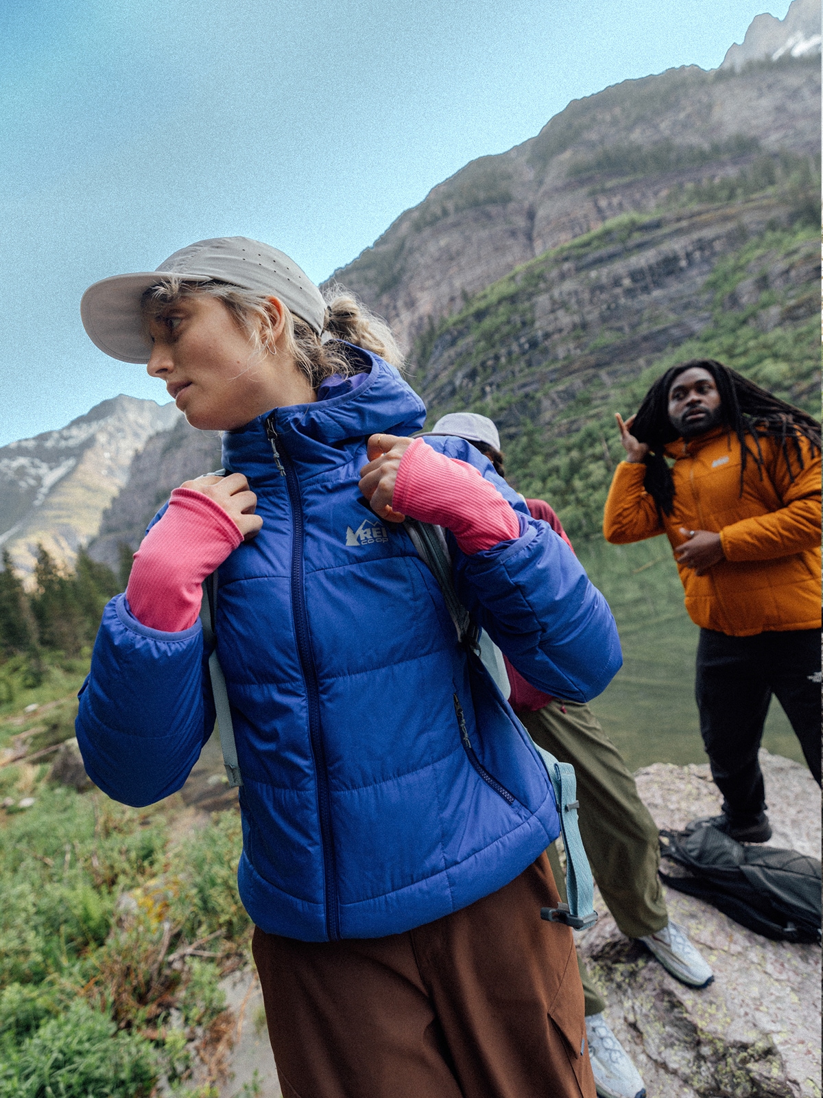 Three people put their backpacks and jackets on before starting their hike.