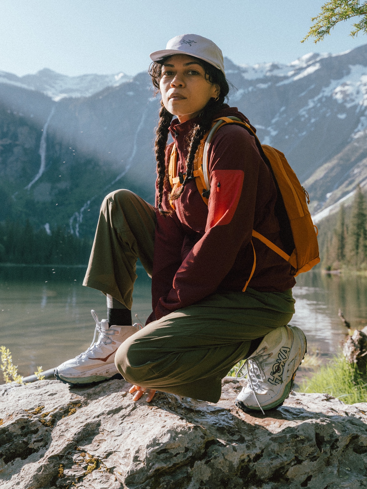 A hiker kneeling on a rock while posing for the camera.