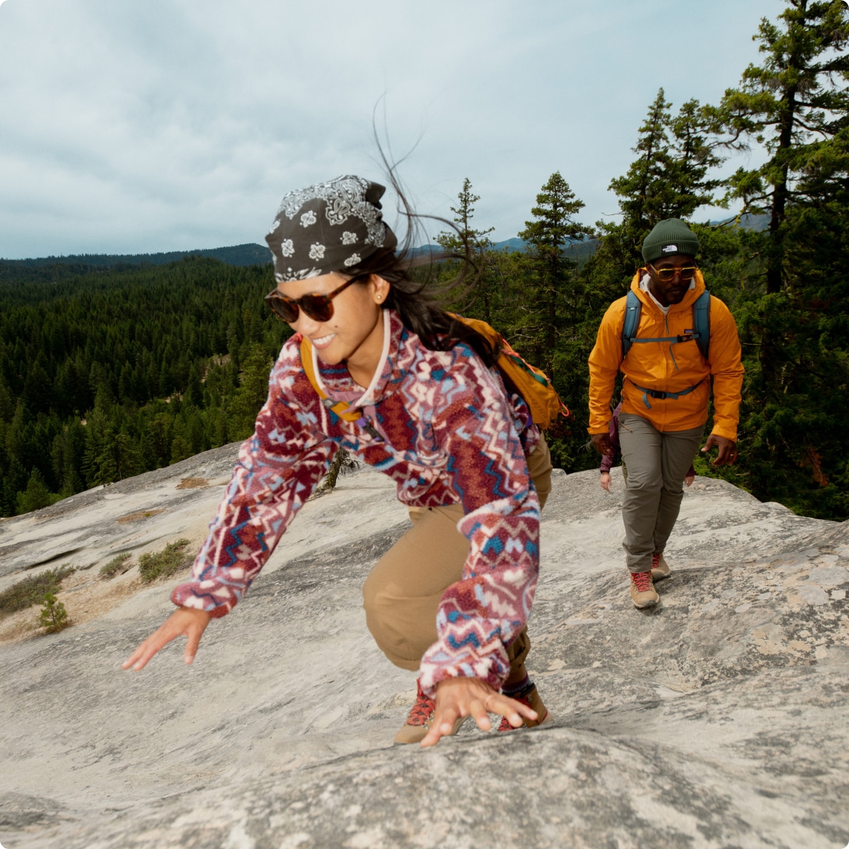 Two people hiking up a large rock.