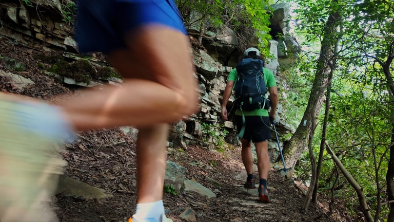 Two people running on a trail with backpacking gear.