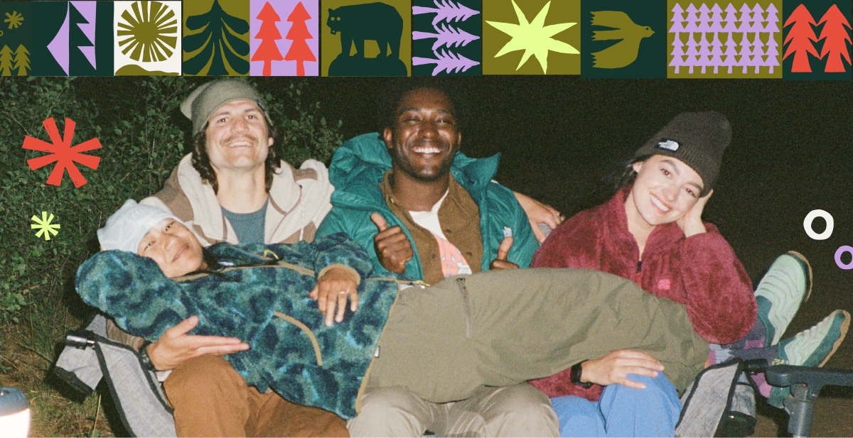 A group of campers smiling for the camera while sharing a chair.