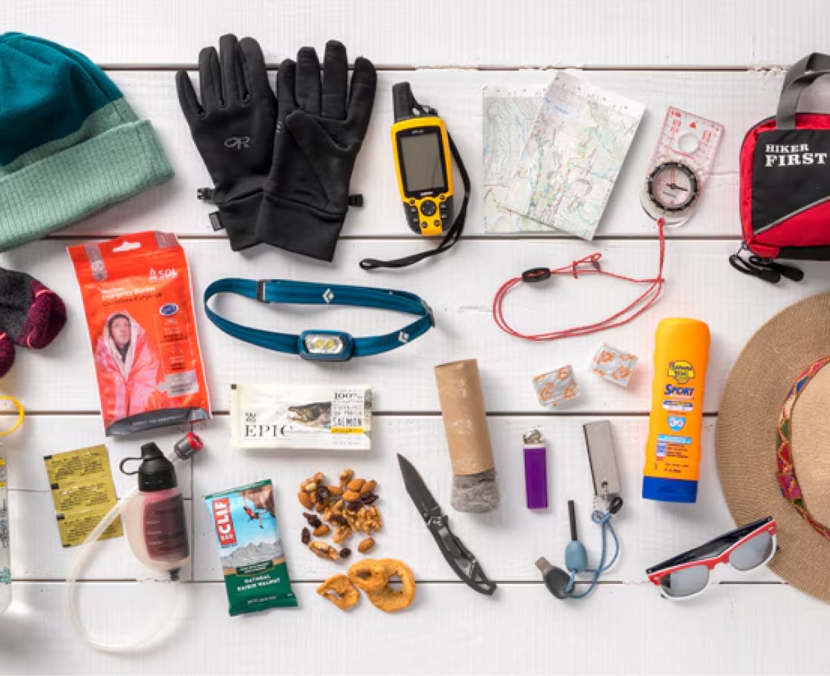 A collage of essential outdoor items spread out on a white wood background.