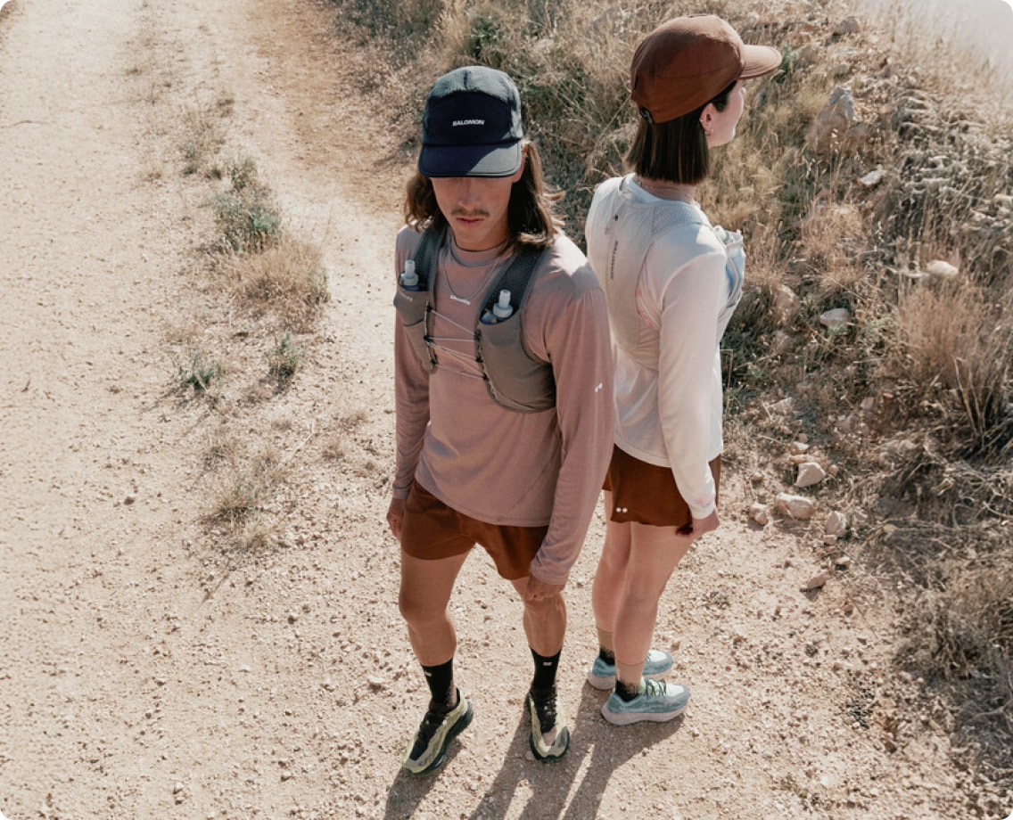 Two people standing back-to-back on a rocky trail.