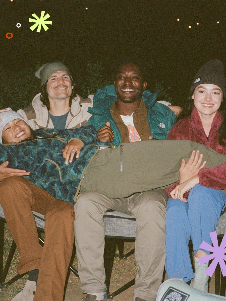 A group of campers sharing a chair and smiling for the camera.