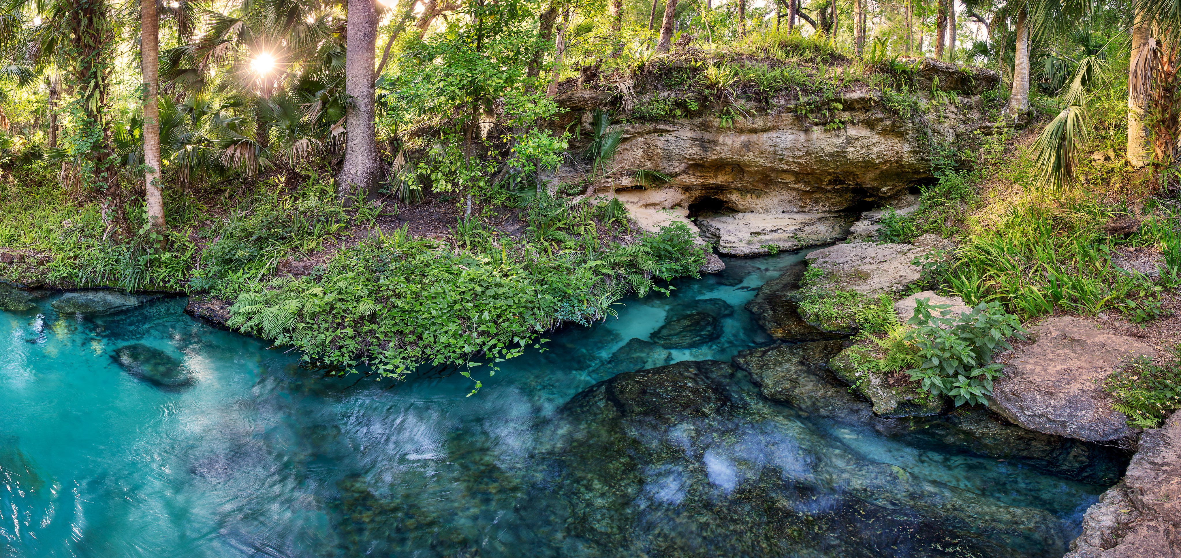 A landscape photo looking down at azure blue water surrounded by jungle foliage