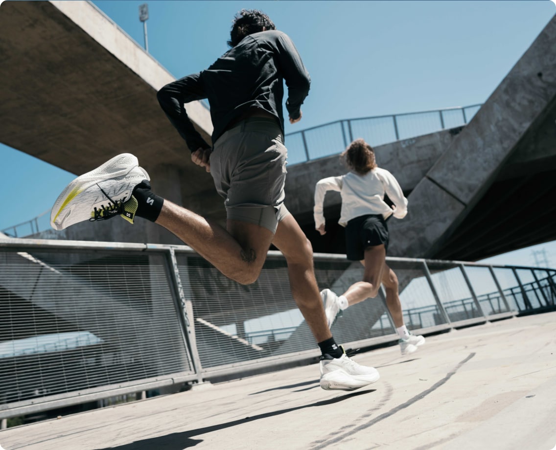 Two people run together through a paved road on a sunny day.
