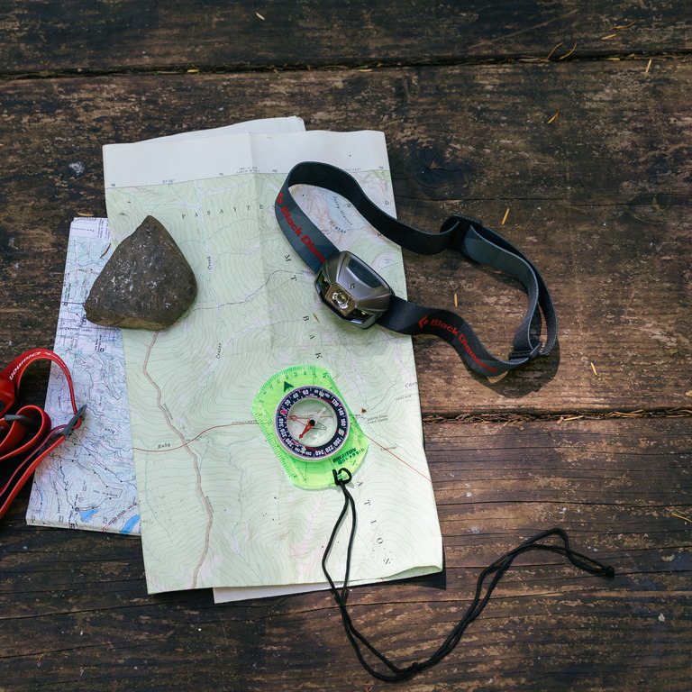 Photo of a map, compass and headlamp