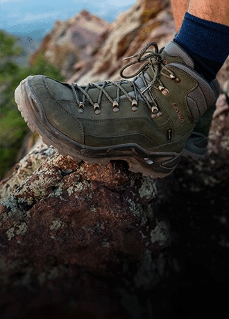 A hiker wears the Lowa Renegade GTX Mid Hiking Boot on a rocky trail