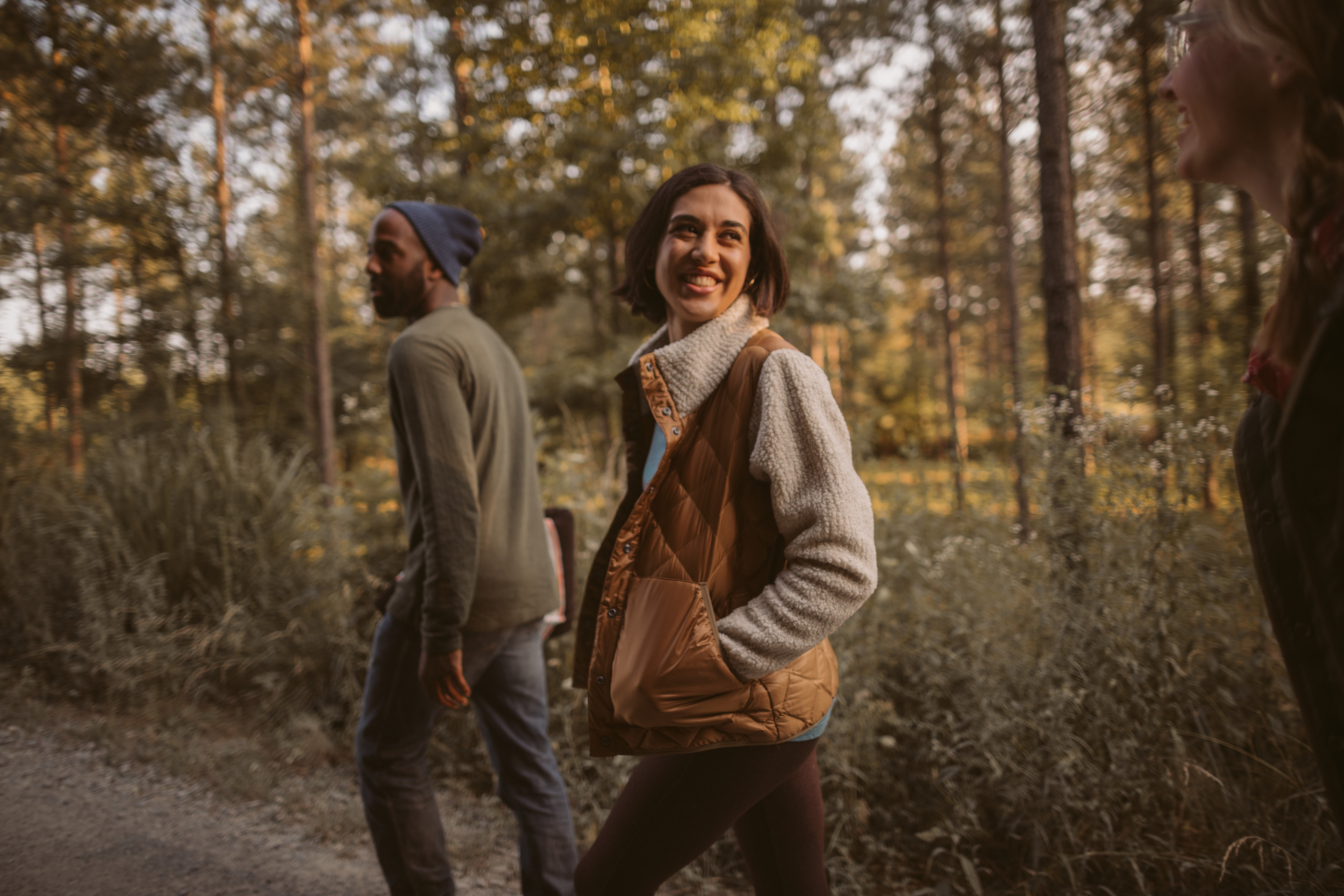 A group of people walk along a dirt path with trees in the background.