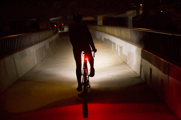 A cyclist riding in the dark with a taillight on.