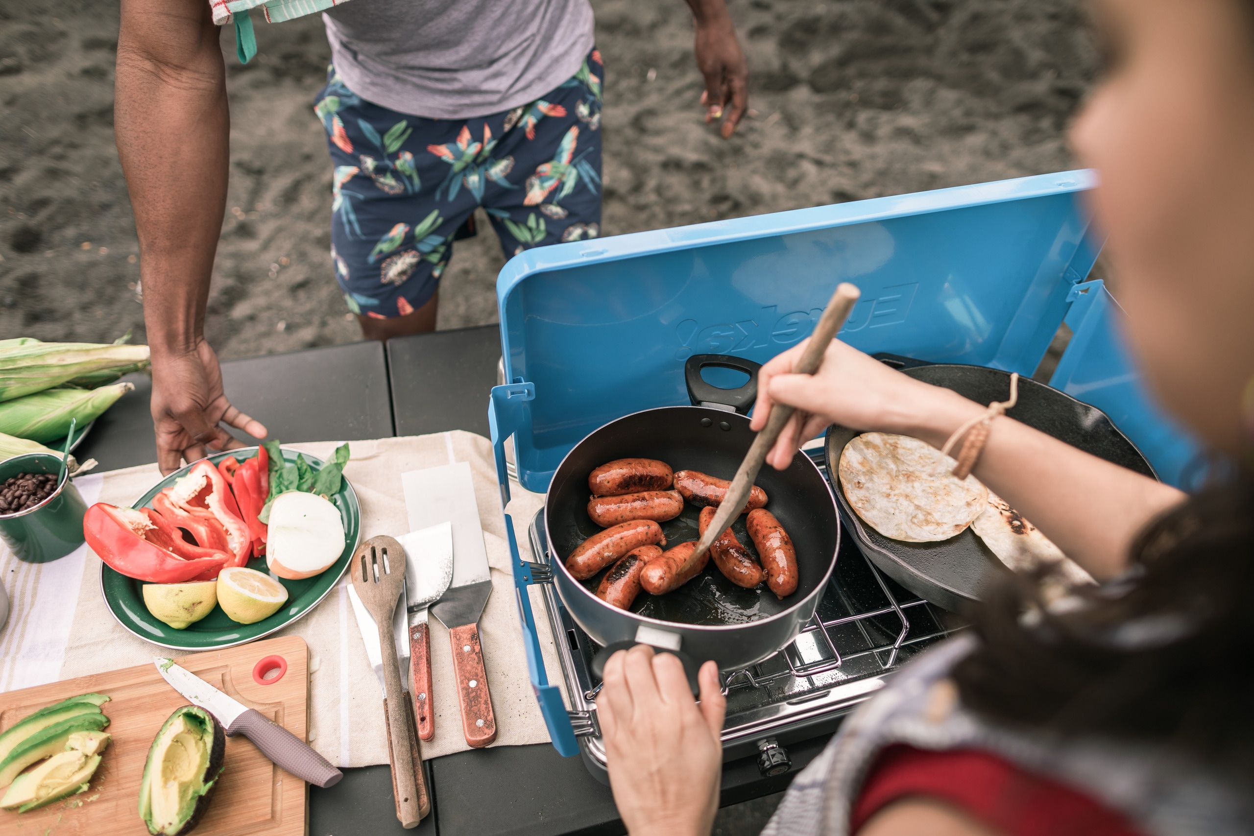 A camper cooks up sausages in a pot at a campsite