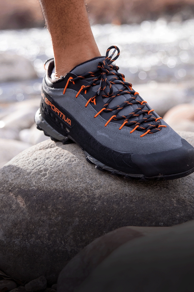 A person wears the La Sportiva TX 4 approach shoe and steps on a rock