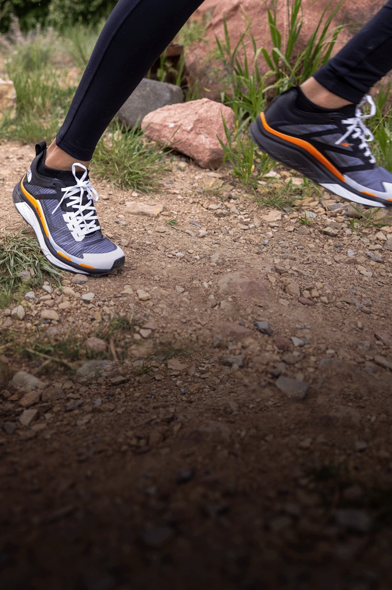 A person wears the The North Face VECTIV Infinite Trail-Running Shoe and steps on a rock