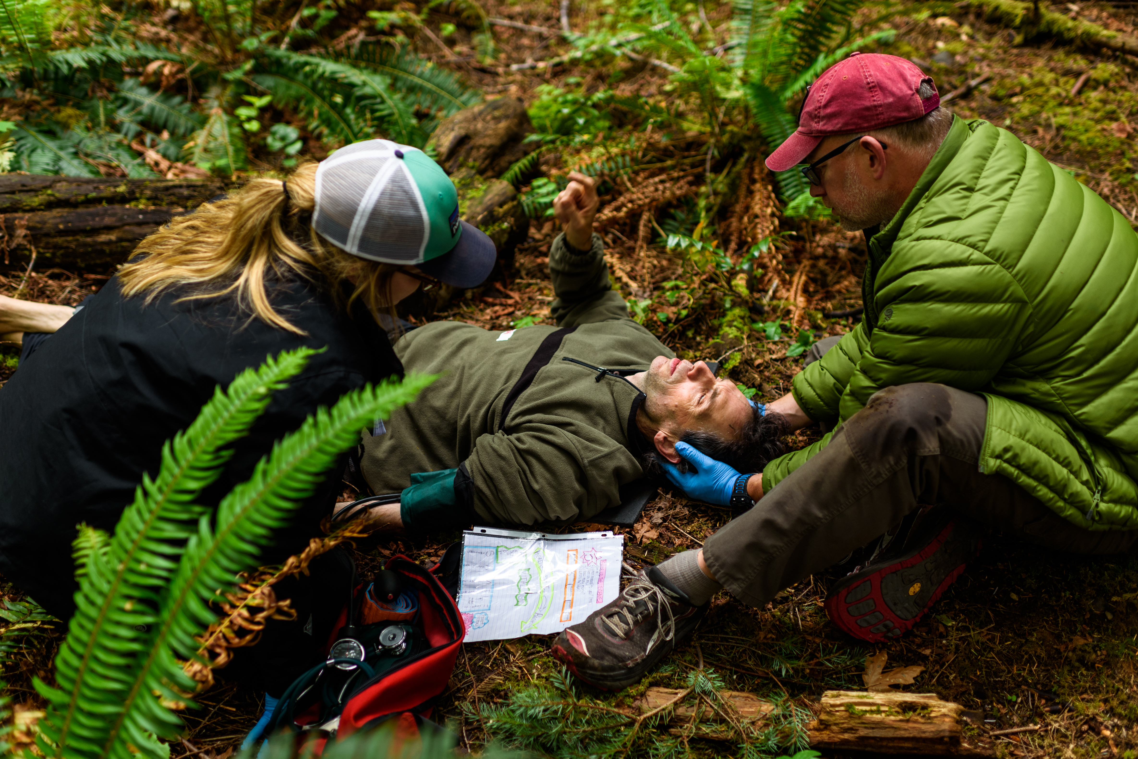 Two people performing rescue health operations on a third person that is on the ground