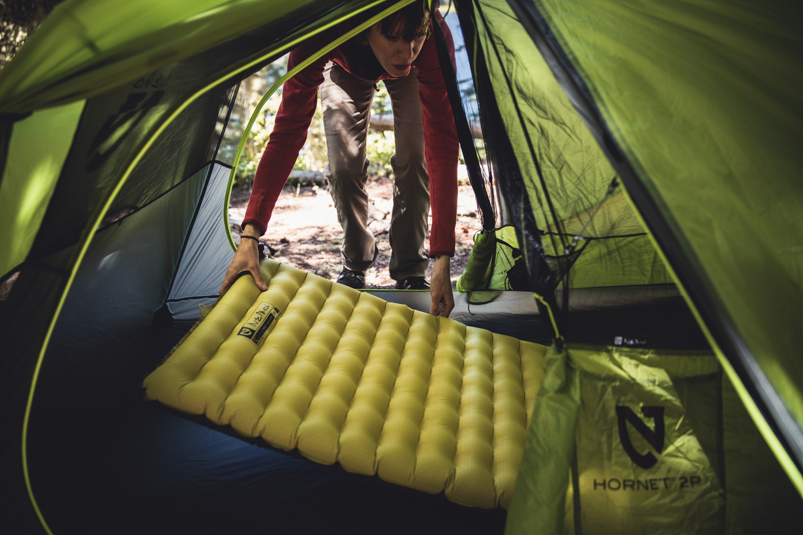 Picture of a person placing a sleeping pad inside a tent.
