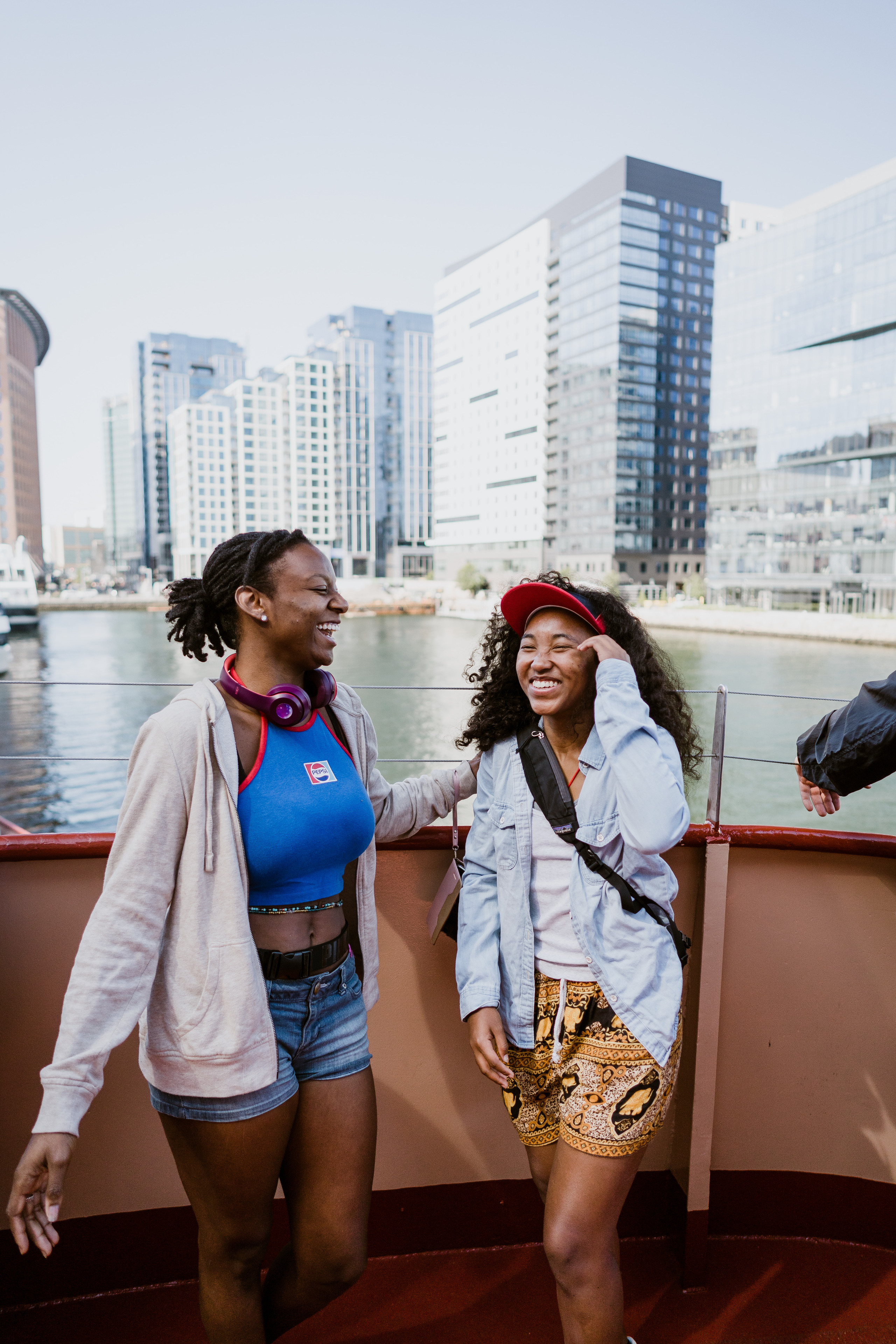 Two people stand in front of a cityscape, laughing together.