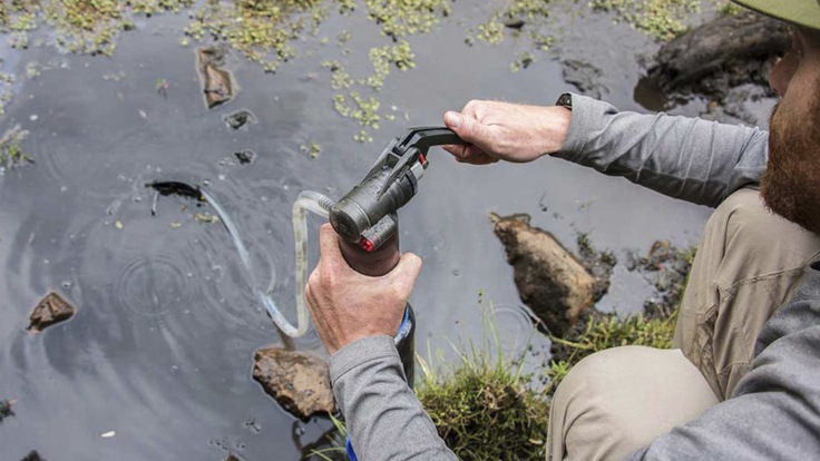 A man using a water filter to treat water in the backcountry