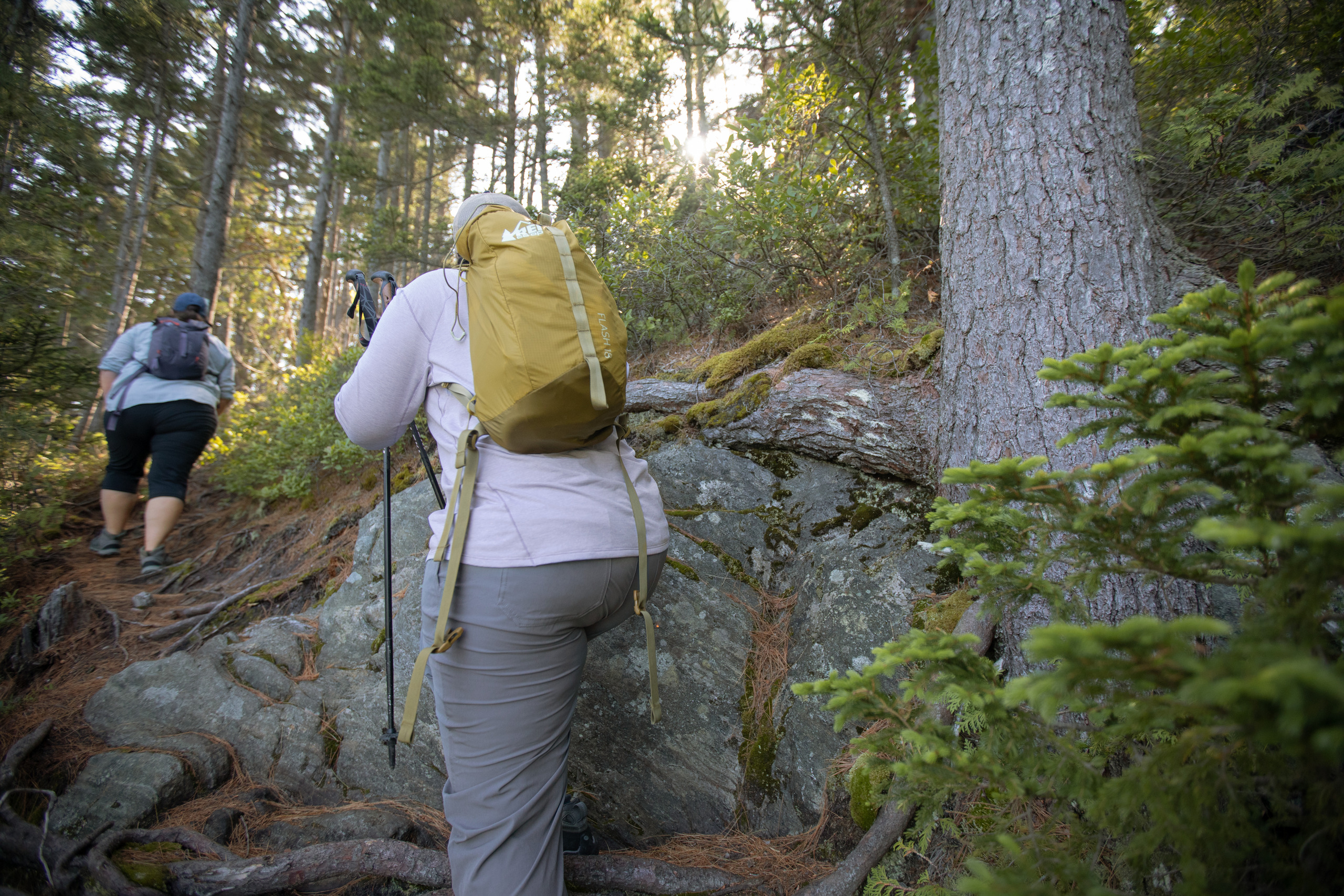 Two people are seen hiking up a steep embankment from behind