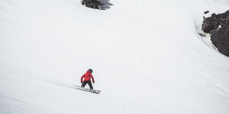 A person in red jacket snowboards down a slope