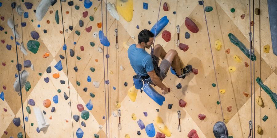 A person hangs from a climbing harness at an indoor climbing gym