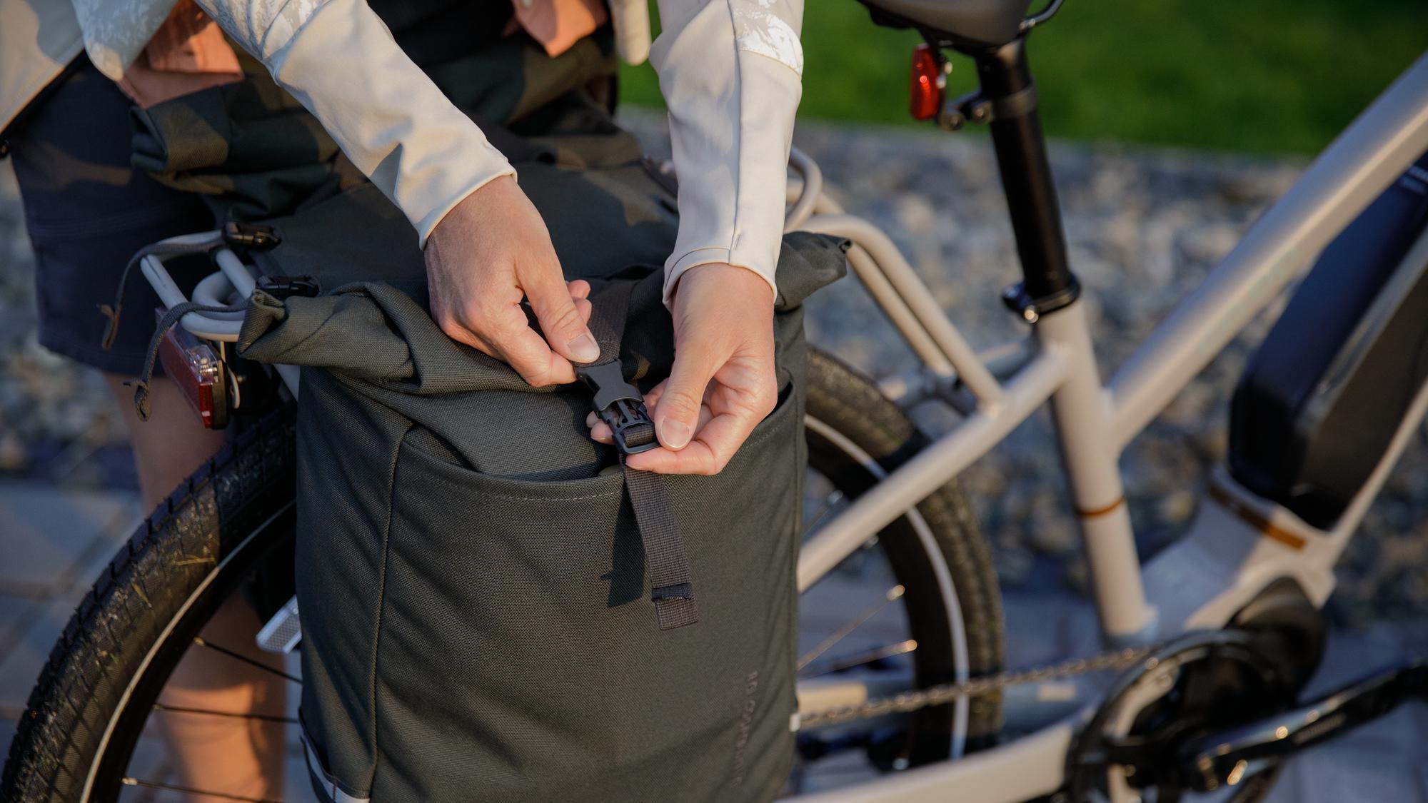 Person latches the buckets on a rear bike pannier bag.
