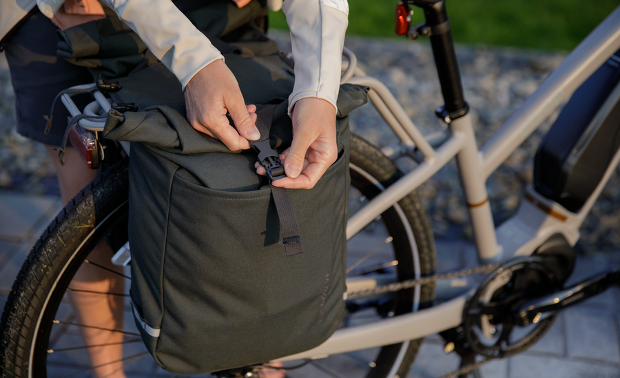 A person buckles a bike bag pannier