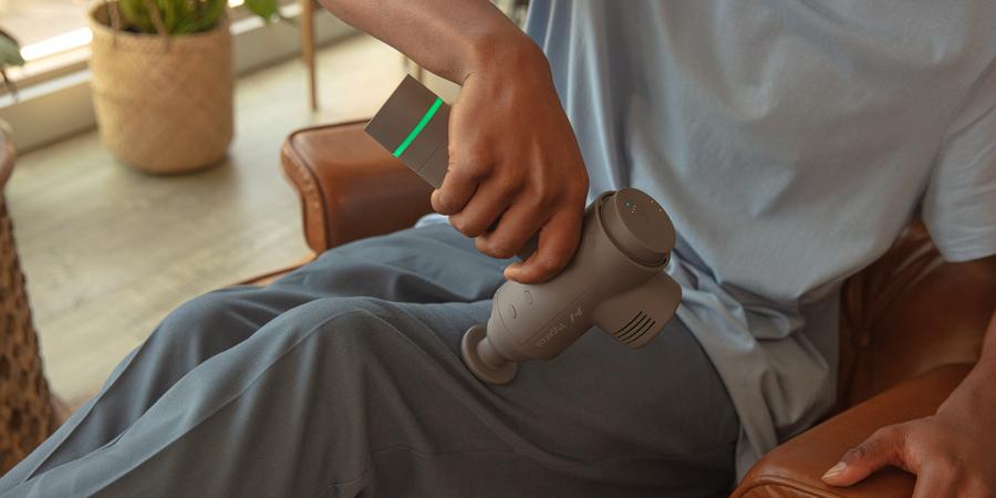 A person uses the Hyperice Hypervolt 2 Bluetooth Massager on their left thigh