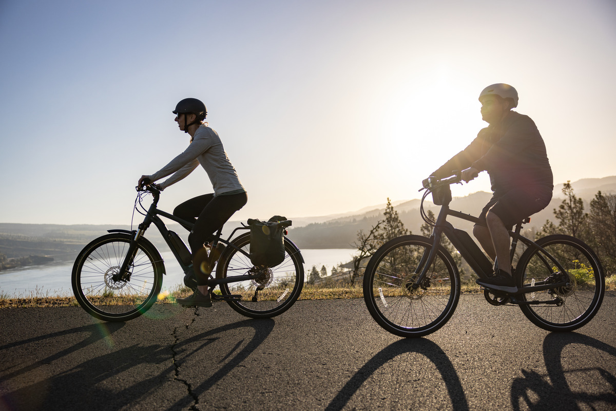 Two people riding e-bikes along a path