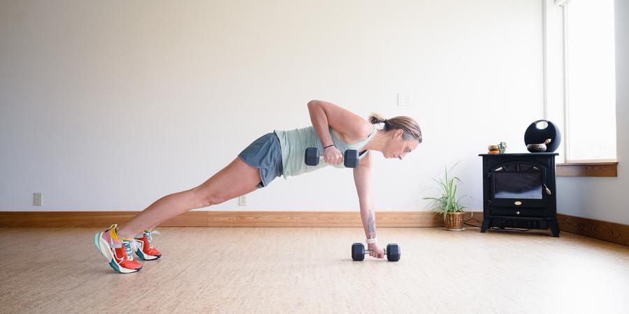 A woman performs plank row with dumbbells in each hand