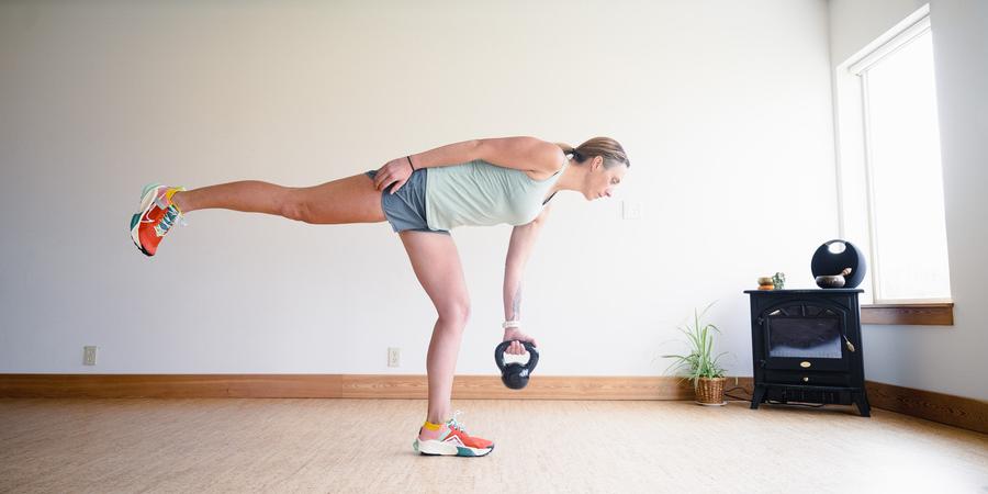 A woman performs a single leg deadlift with a kettlebell
