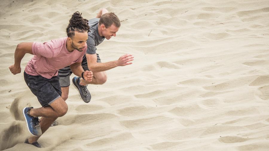 Two men running up a dune