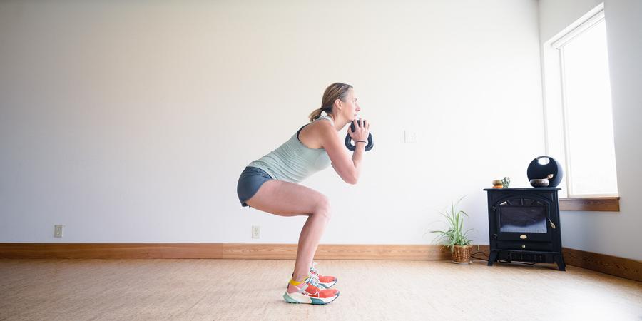A woman squats while holding a kettlebell
