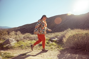 Woman hiking in colorful orange leggings and a multi colored fleece